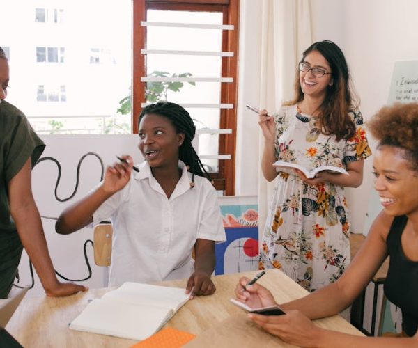 A diverse group of women engaged in a lively office meeting, sharing ideas and brainstorming together.